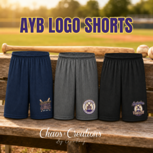 Amsterdam Youth Baseball athletic shorts in navy, charcoal, and black displayed on a dugout bench with a baseball field background.